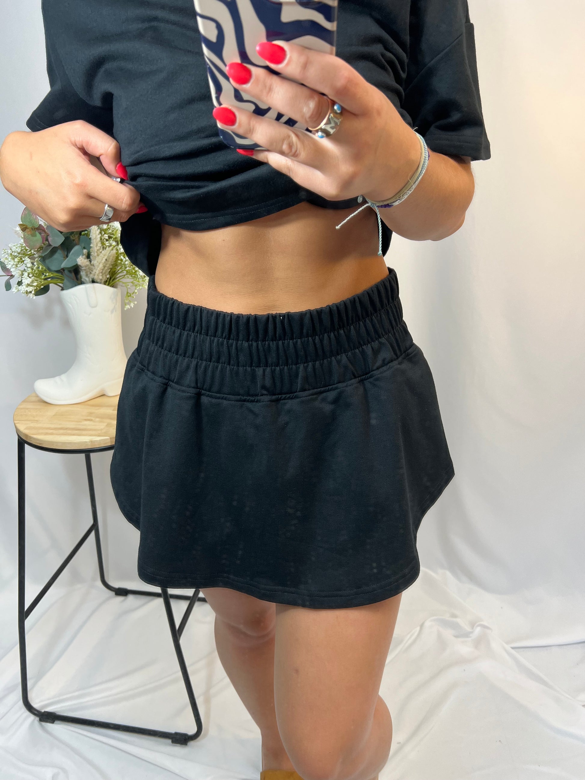 Close-up of black cropped tee and ruffle high-waist skort set, women’s matching top and skirt shorts outfit
