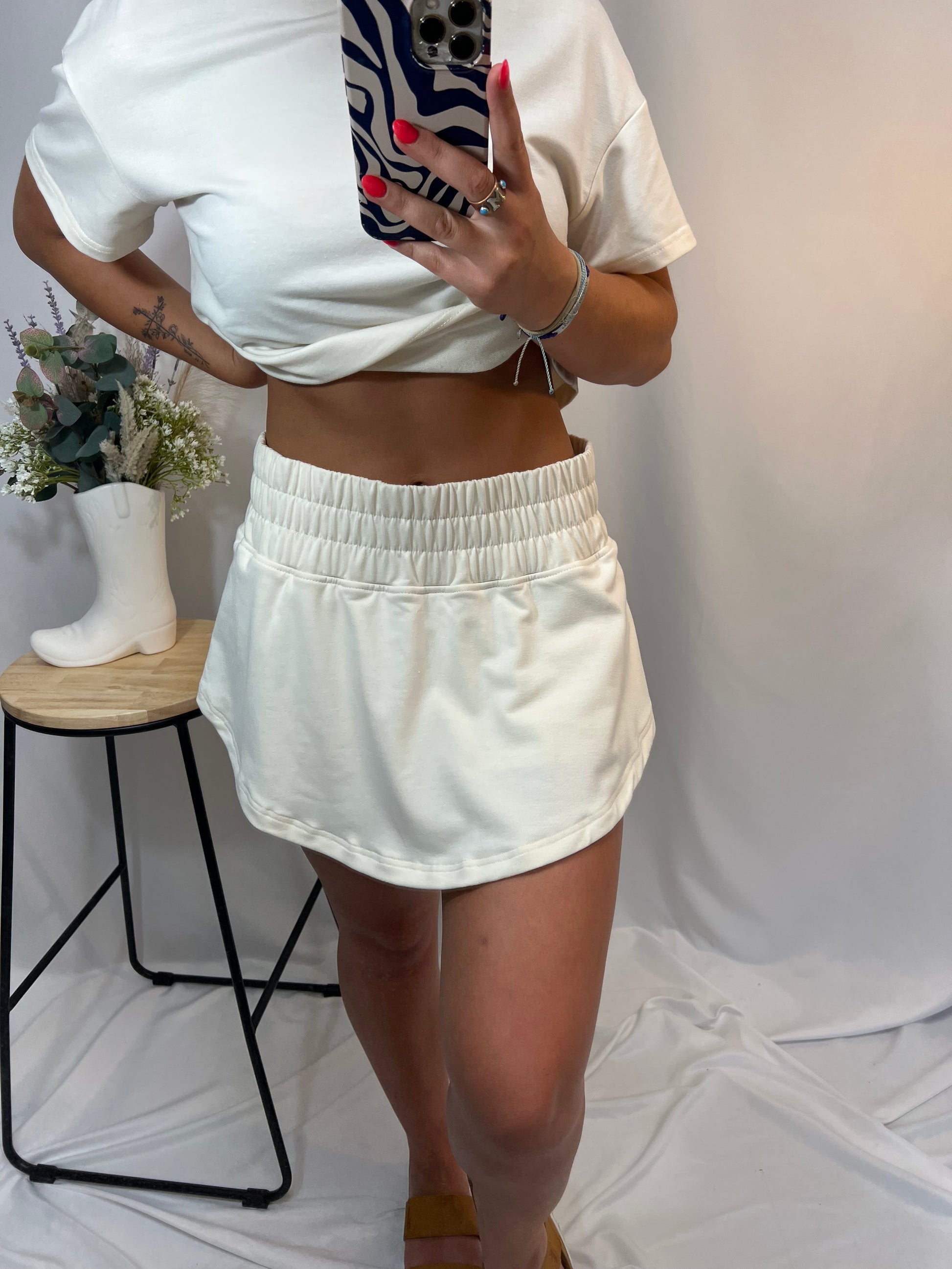 Close-up of ivory cropped tee and ruffle high-waist skort set, women’s matching top and skirt shorts outfit