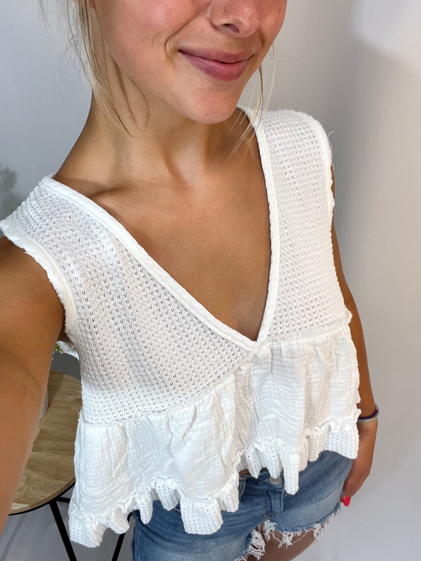 Close-up of white sleeveless thermal babydoll tank, women’s cropped waffle knit top with flowy fit